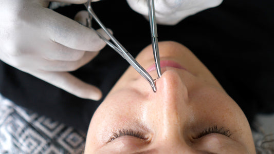 Professionele piercer zet een neuspiercing bij een cliënt.
